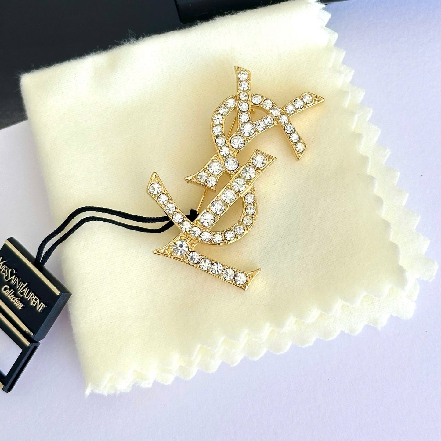 Gold brooch with crystal details on a Yves Saint Laurent branded cloth