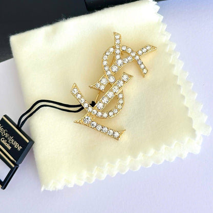 Gold brooch with crystal details on a Yves Saint Laurent branded cloth